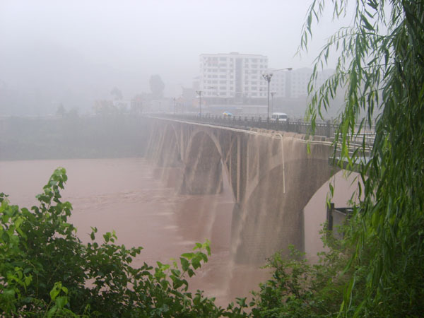 Dated bridge or water-control structure above brown water in Bazhou
