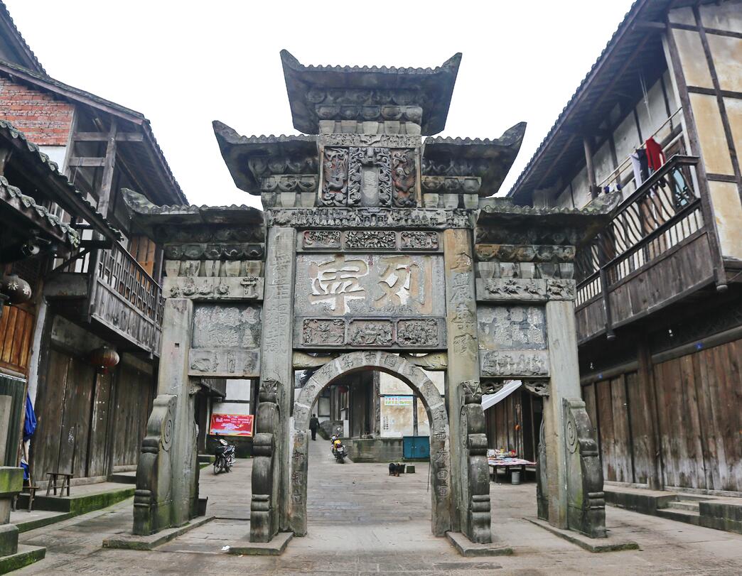 Carved stone archway within the living timber streetscape of Shiqiao