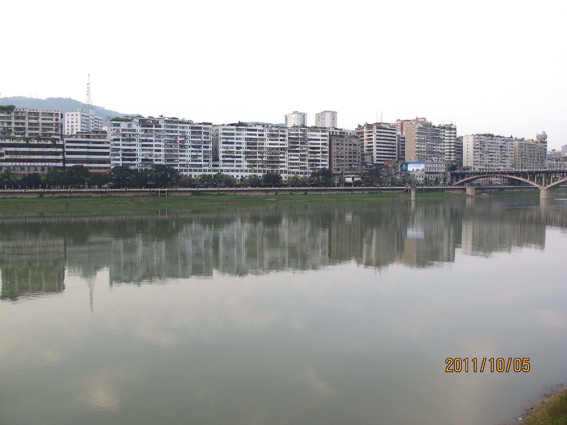 Dated riverfront blocks reflected in the Zhou River at Tongchuan