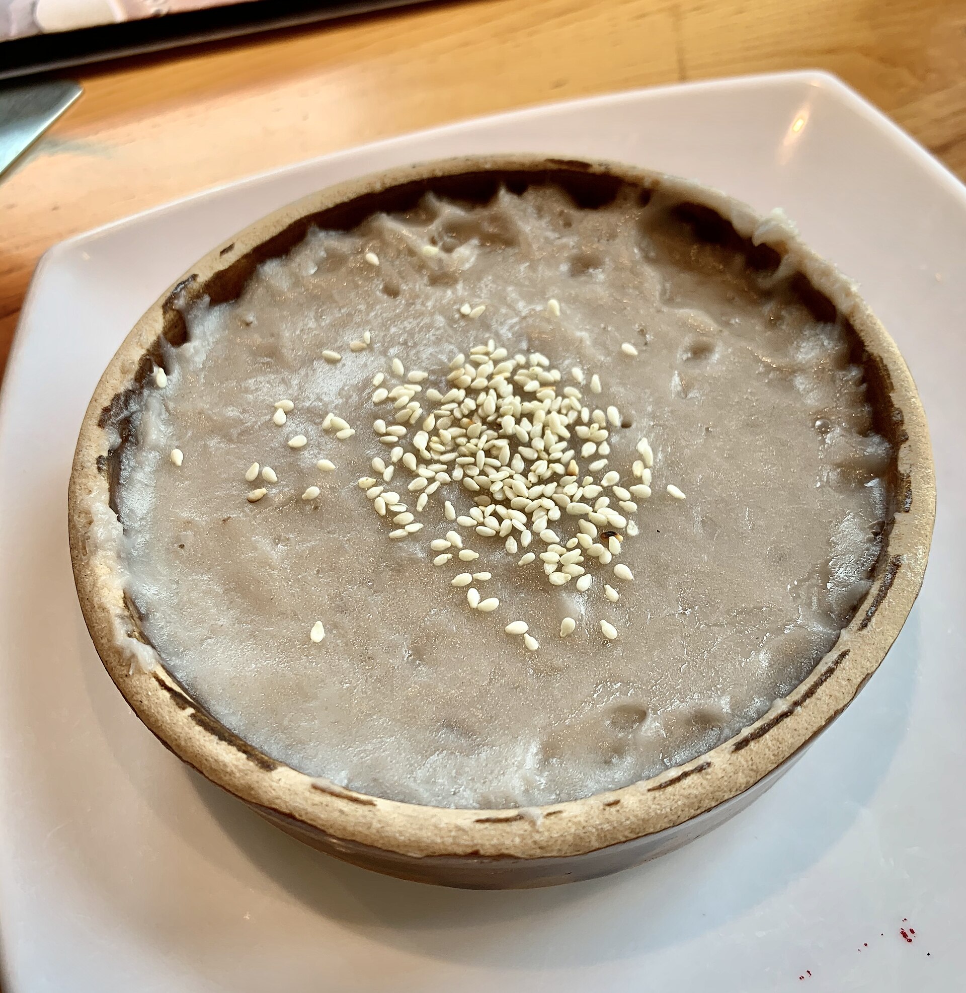 Smooth taro paste topped with sesame in a shallow earthenware bowl
