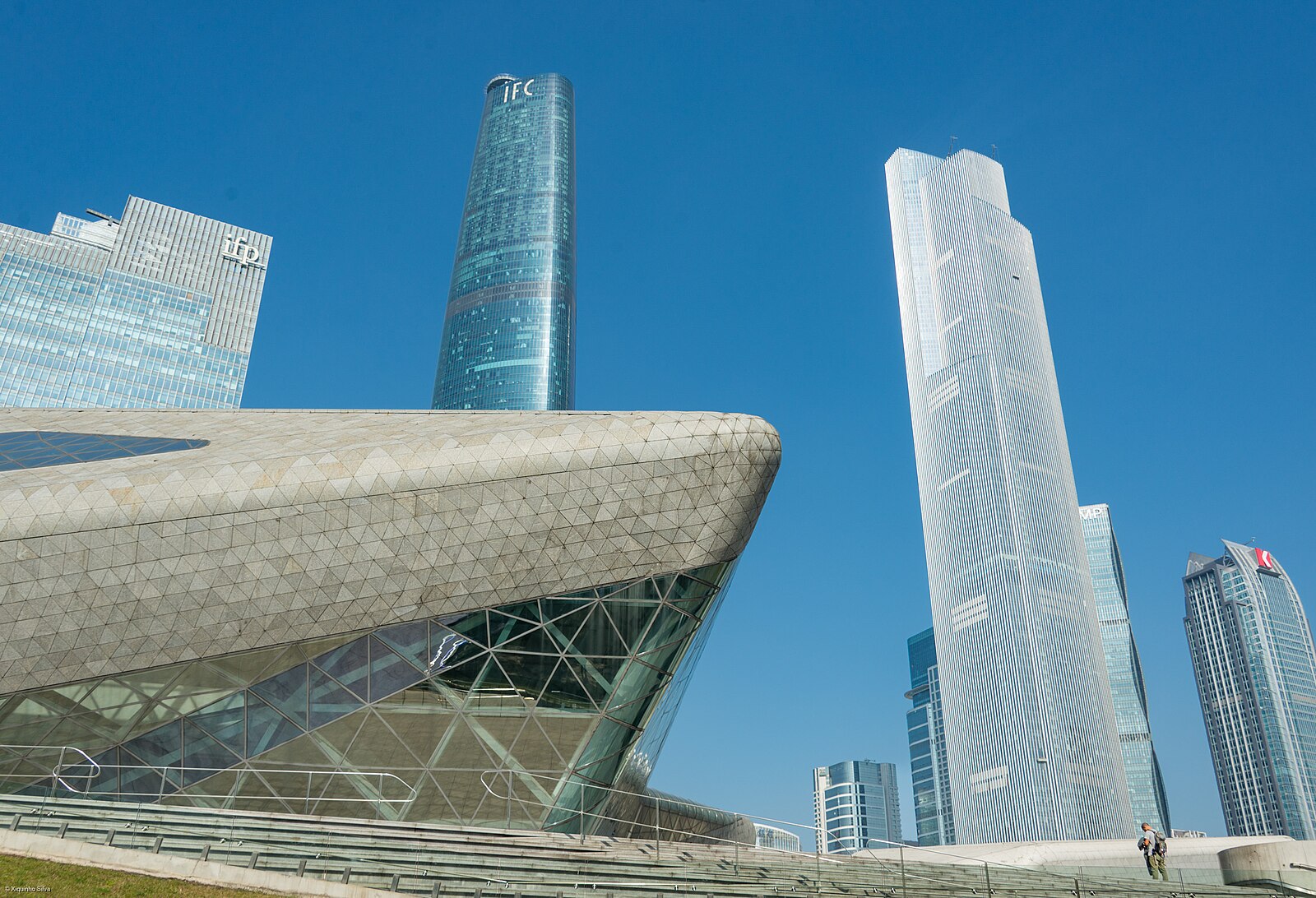 Faceted opera-house volume beneath Zhujiang New Town towers