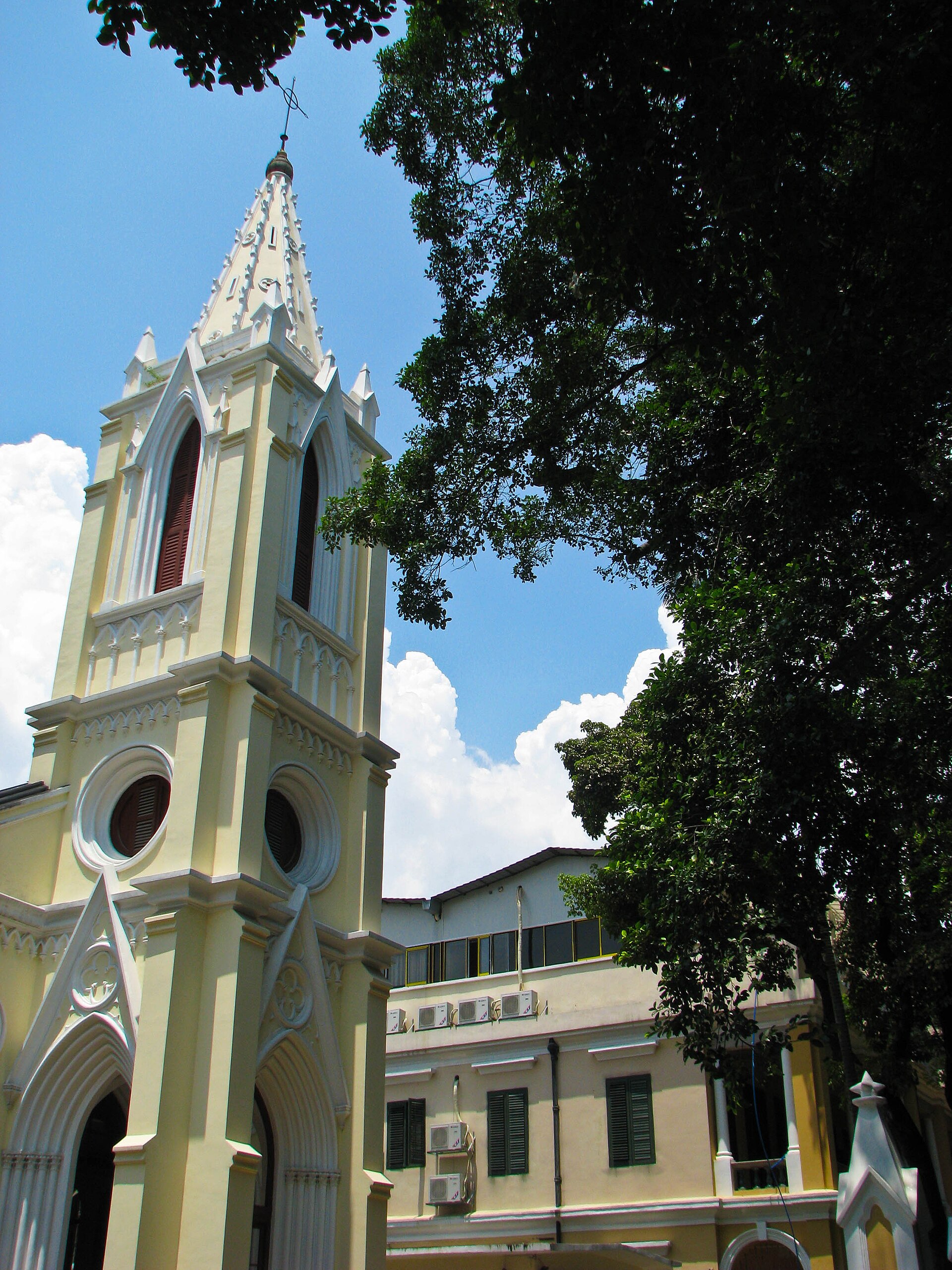Pale church tower framed by trees on Shamian