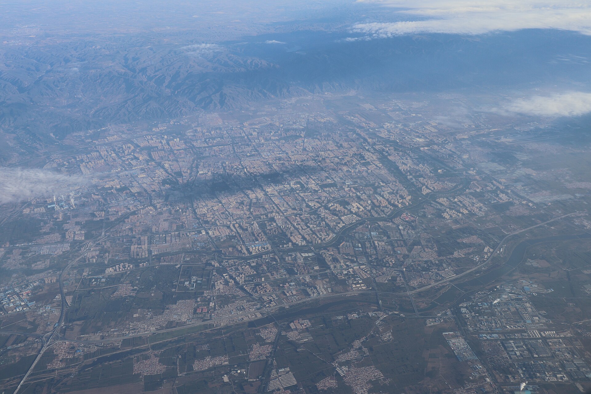 Oblique aerial view of Hohhot's street grid, fields and mountains