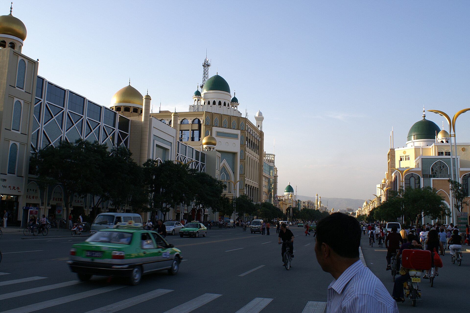 Dated boulevard with dome-shaped facades, cars, cyclists and pedestrians