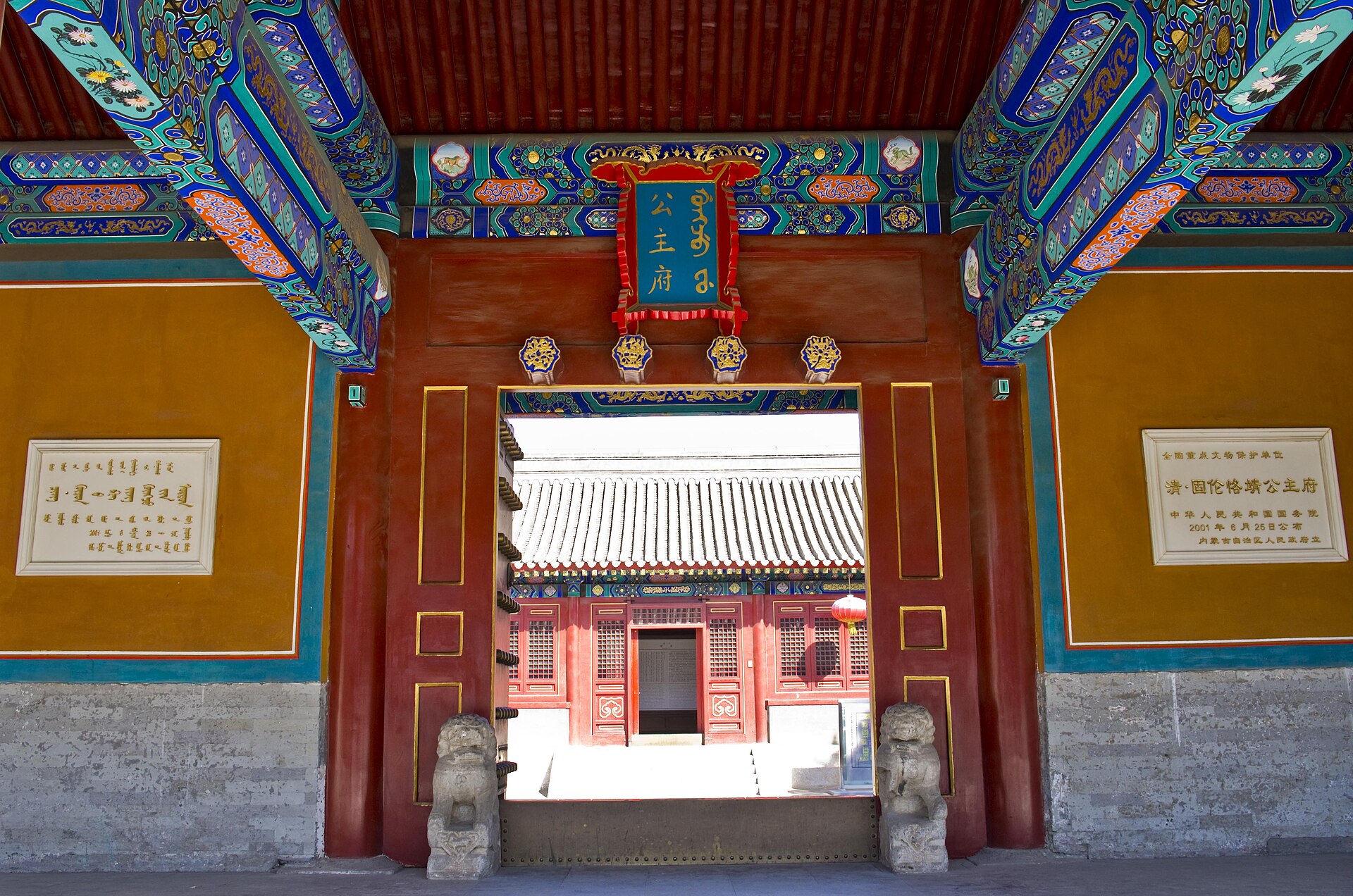 Painted threshold, plaque, stone lions and red courtyard buildings at the Princess Mansion