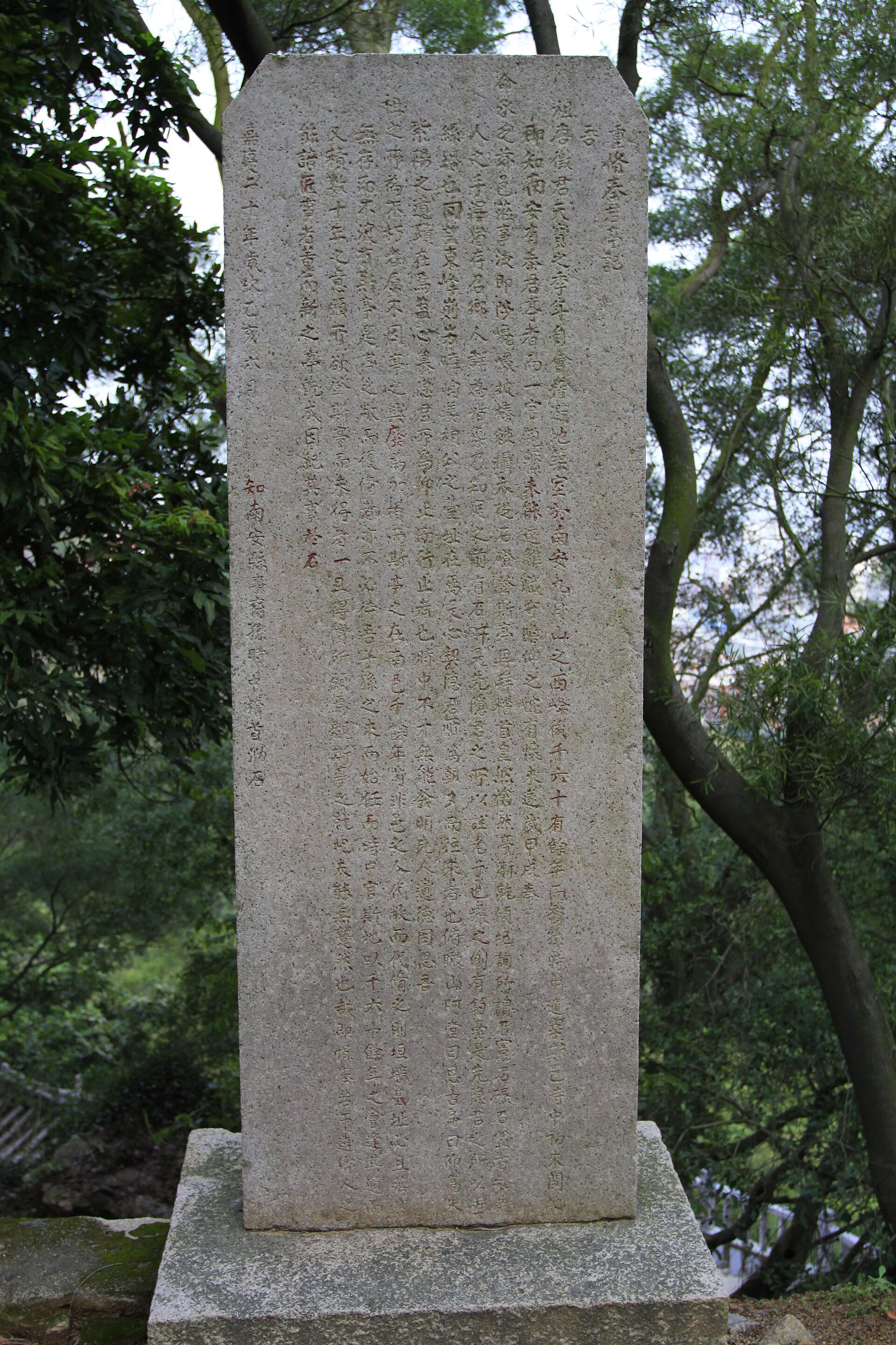 Tall freestanding inscribed stele in the wooded Jiuri Mountain landscape