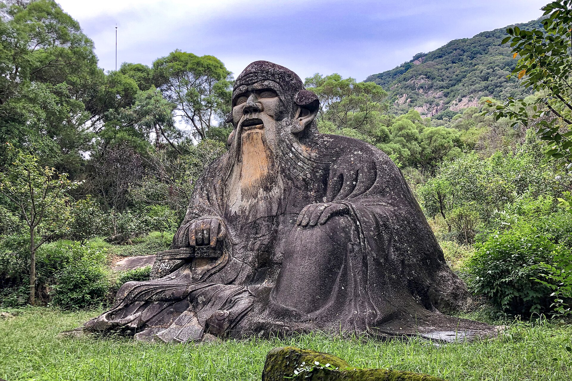 Large seated rock-cut Laozi statue against woodland on Qingyuan Mountain