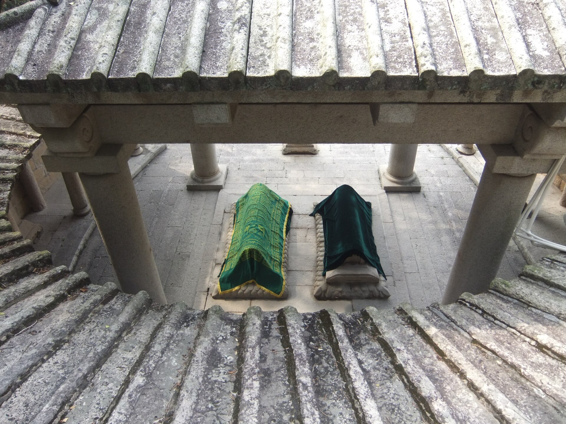 Two cloth-draped tombs viewed through a stone pavilion at Lingshan Islamic Cemetery