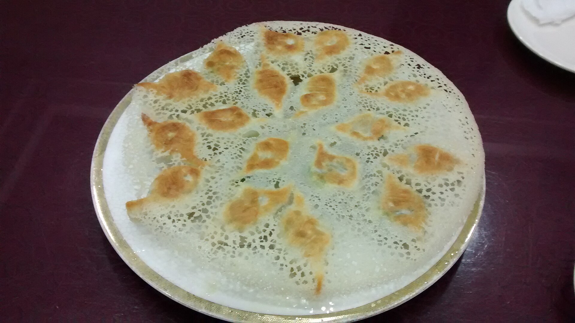 Pan-fried dumplings connected by a thin crisp starch lattice