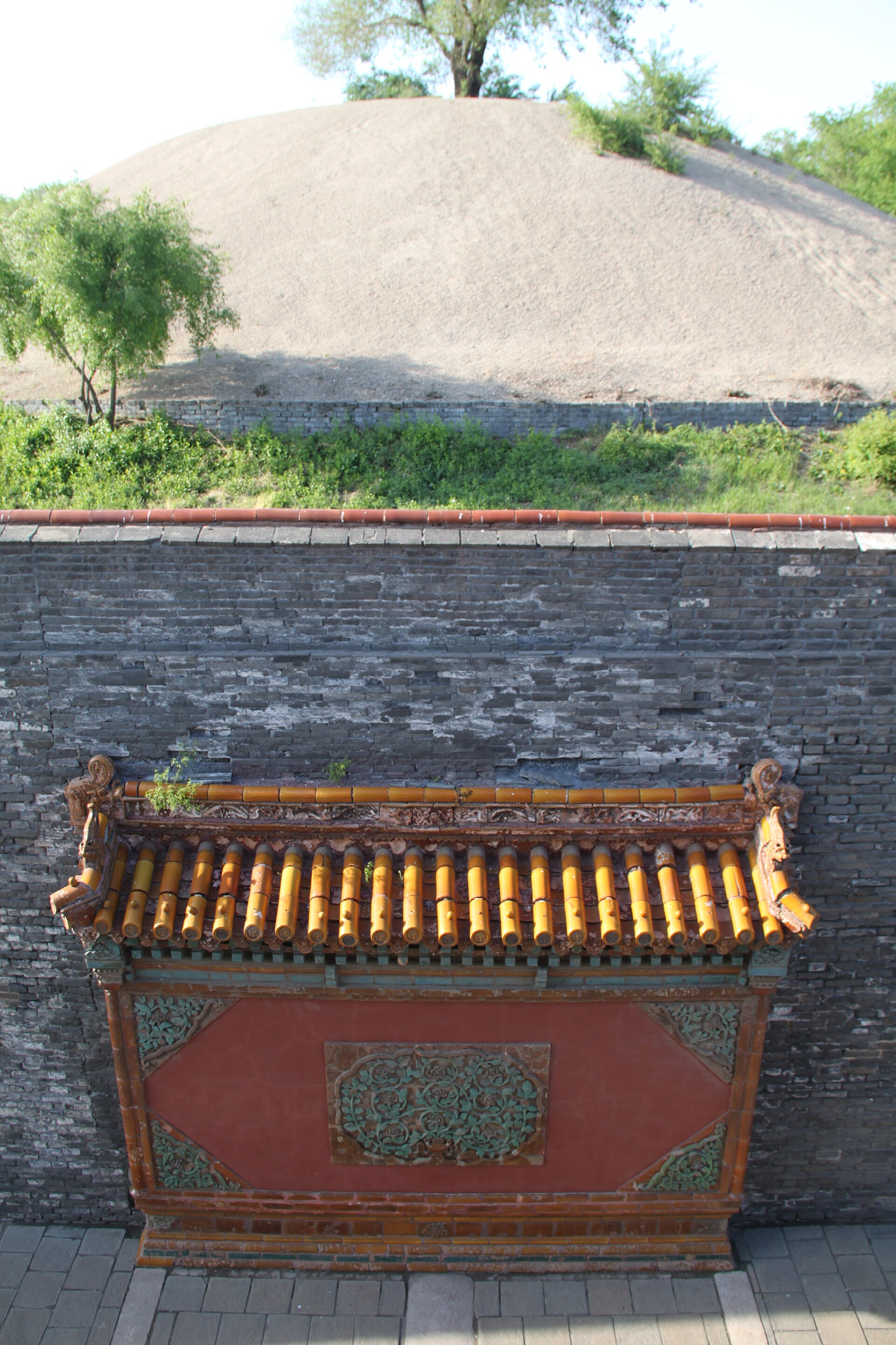 Close view of a tiled wall niche, grey brick and mound at Zhaoling