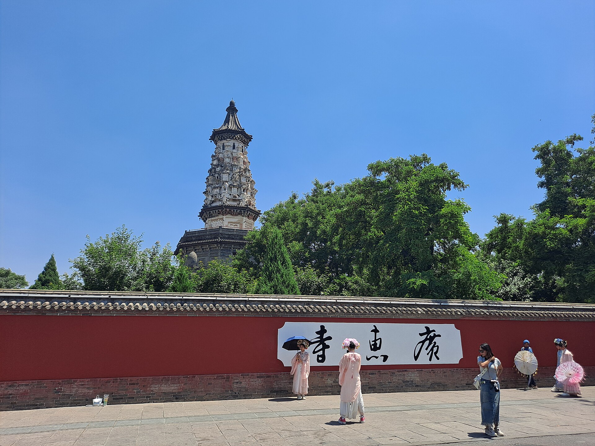 Hua Pagoda rising behind trees and enclosure walls with visitors in Zhengding