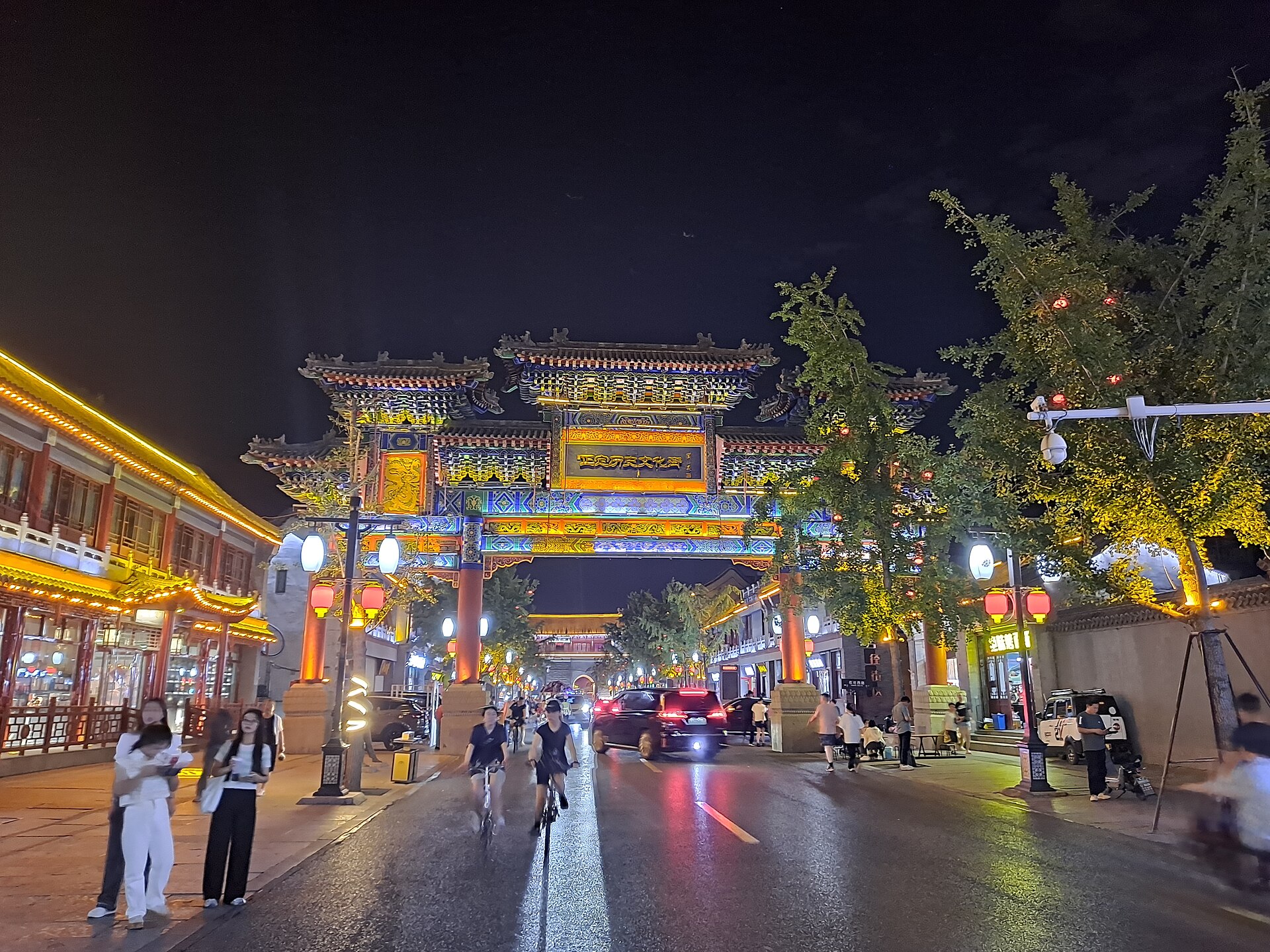 Cars, pedestrians and illuminated gateway on a Zhengding street at night