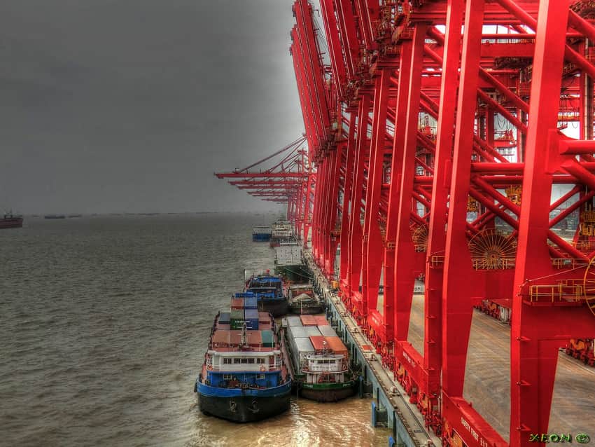 Red quay cranes, barges and ships at a Taicang container terminal