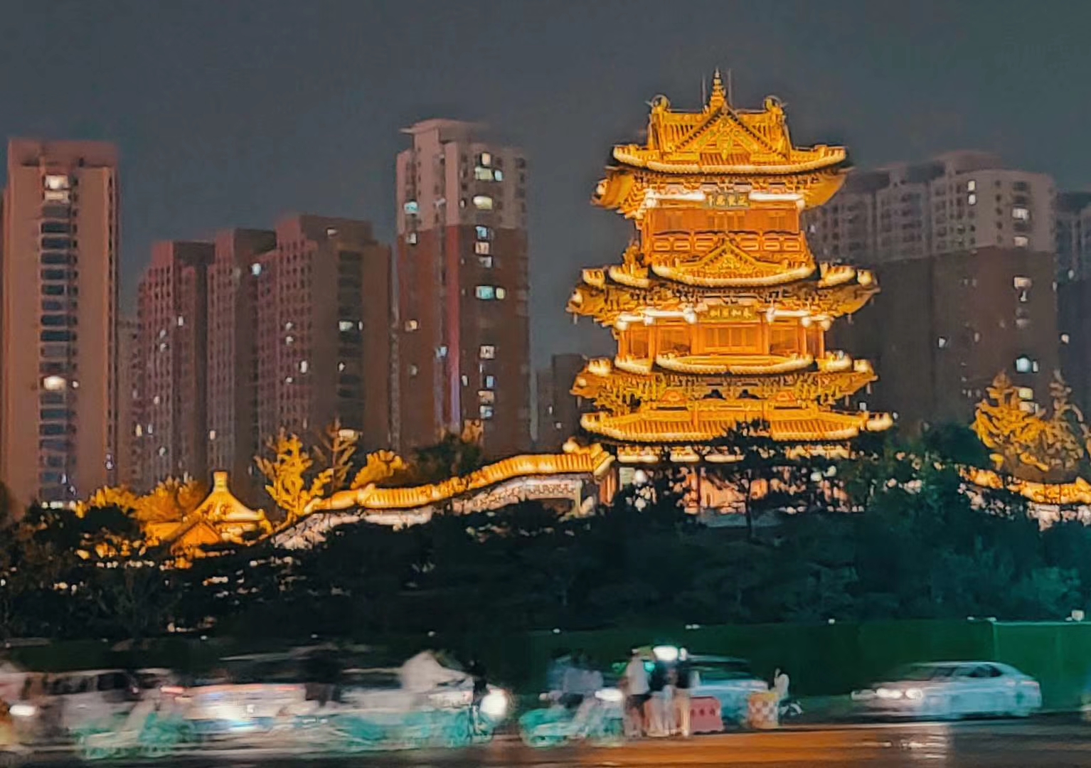 Illuminated traditional-style pavilion, housing towers and traffic in a 2019 Taiyuan night view