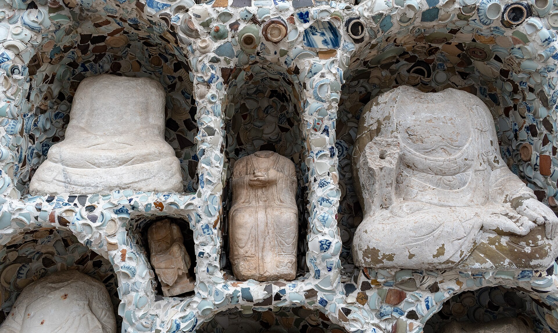 Stone figures in niches and porcelain-shard surface at Tianjin Porcelain House