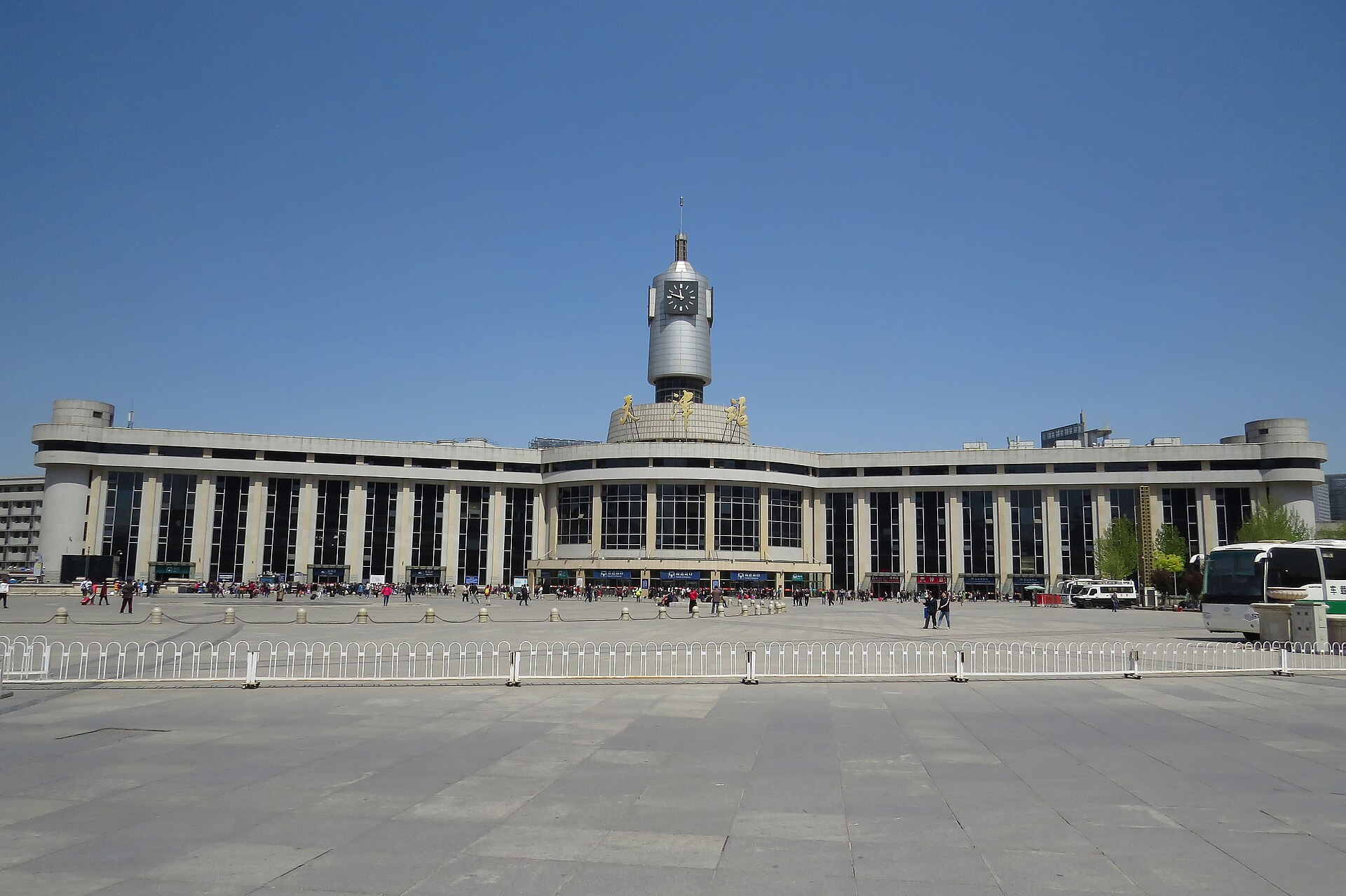 Frontal 2016 view of Tianjin Railway Station, clock tower, plaza and passengers