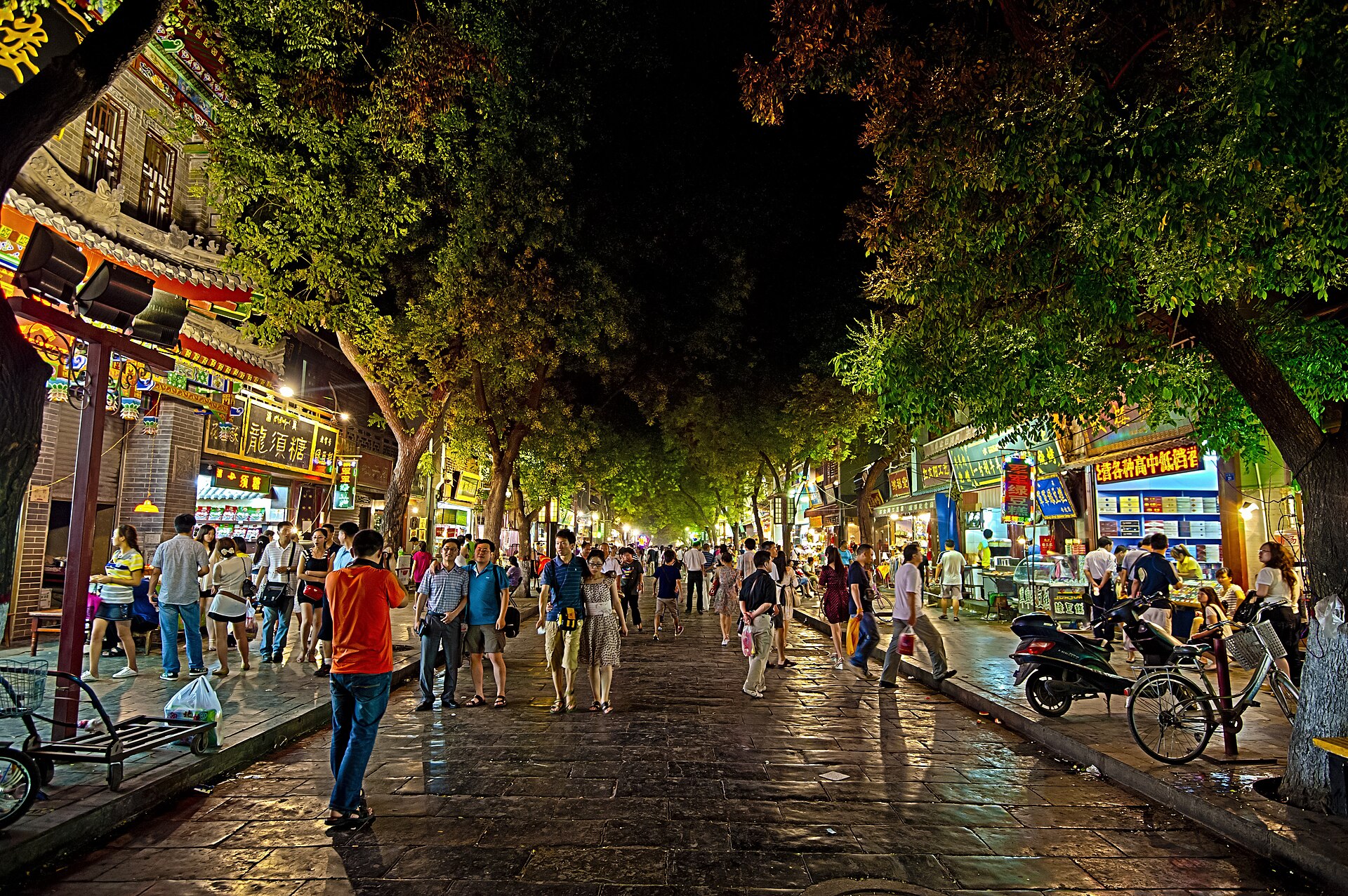 Busy illuminated night street with shops and pedestrians in Xi'an's Muslim Quarter