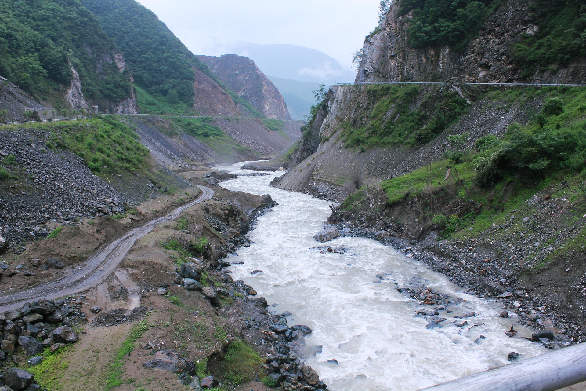 Fast Dong River between steep road-cut slopes in Baoxing