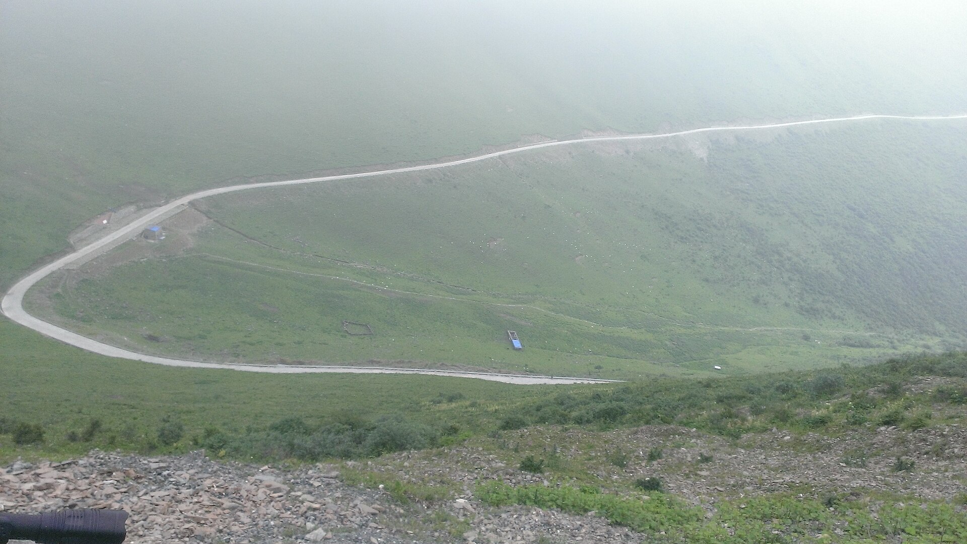 Switchback road across foggy open highland slopes in the Jiajin Mountains